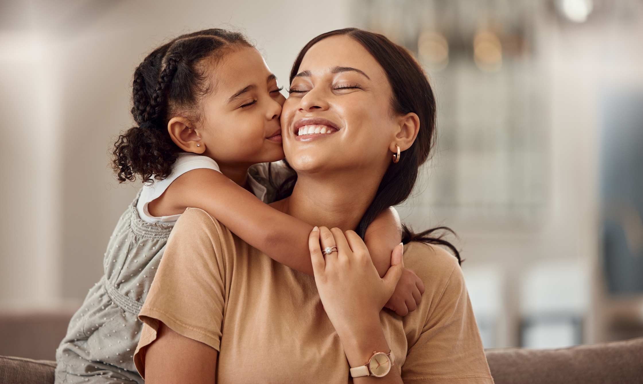 Smiling mother with daughter kissing cheek.